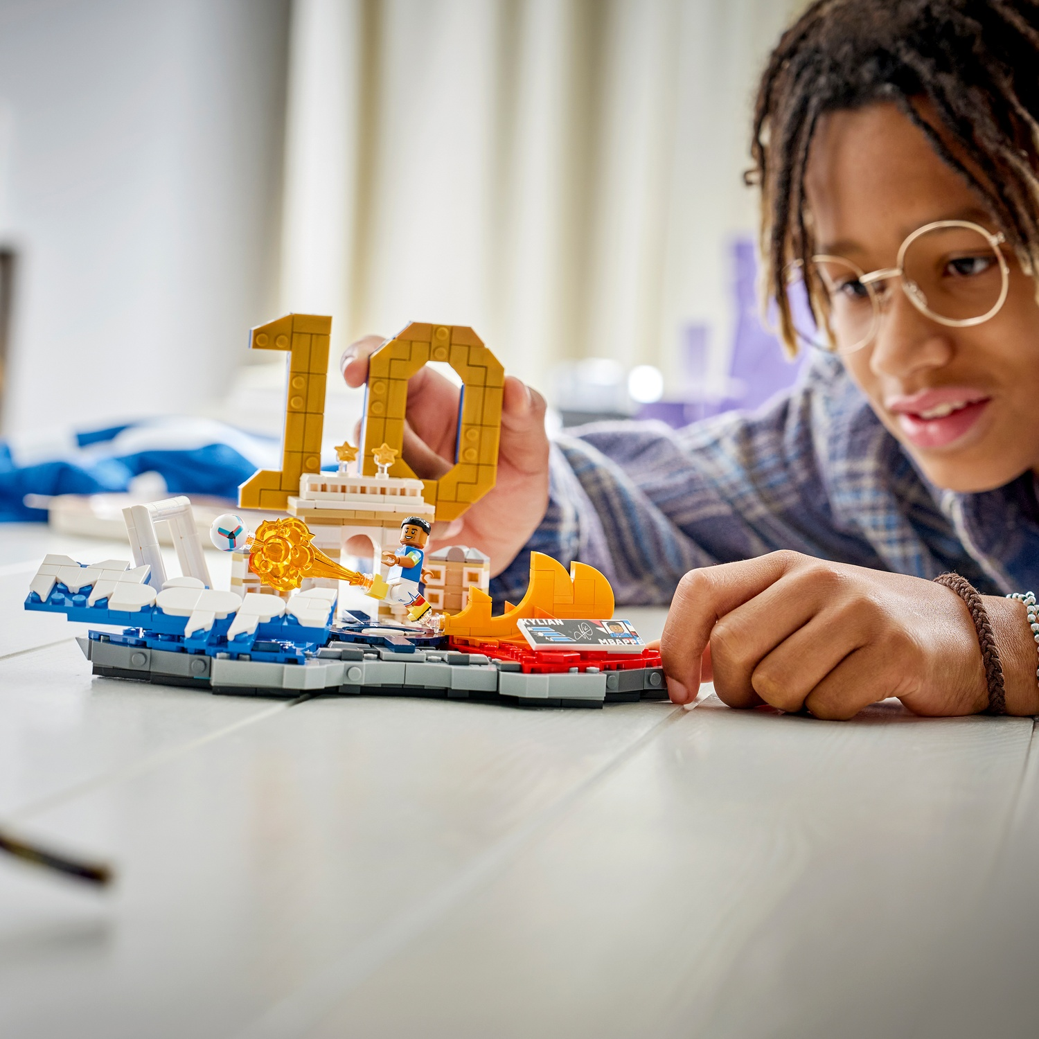 Un bambino gioca con un set Lego raffigurante un calciatore e il numero 10.
