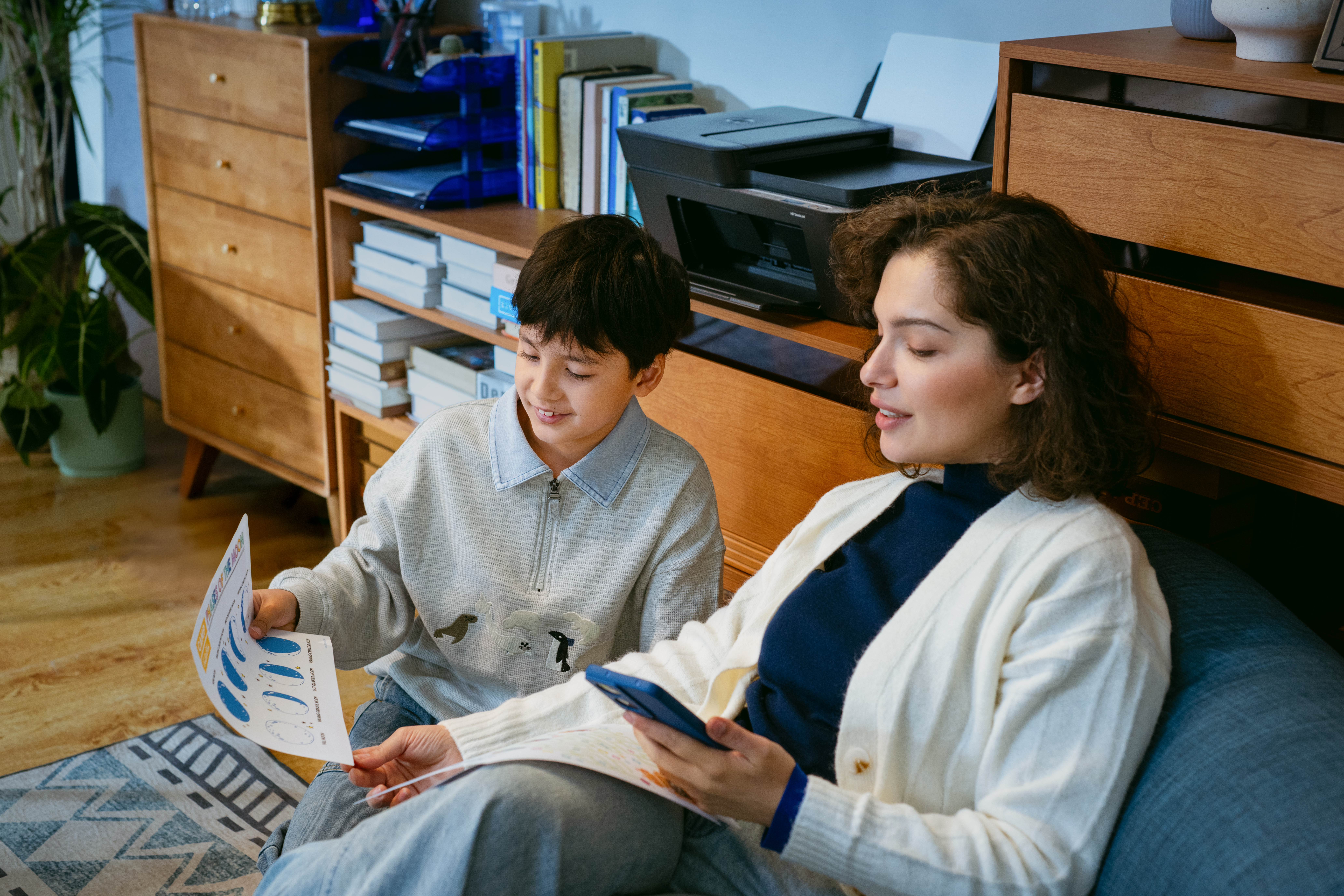 Kobieta i chłopiec siedzą i patrzą na kartkę papieru.