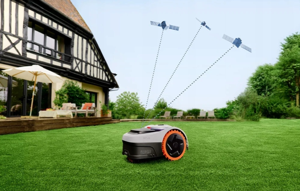 Robot koszący trawę na zielonym trawniku przed domem, z satelitami na niebie.