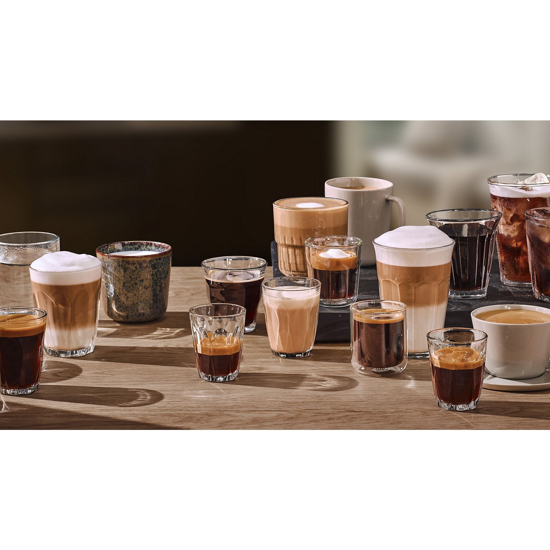 Asortyment kaw w szklankach i kubkach na drewnianym stole.