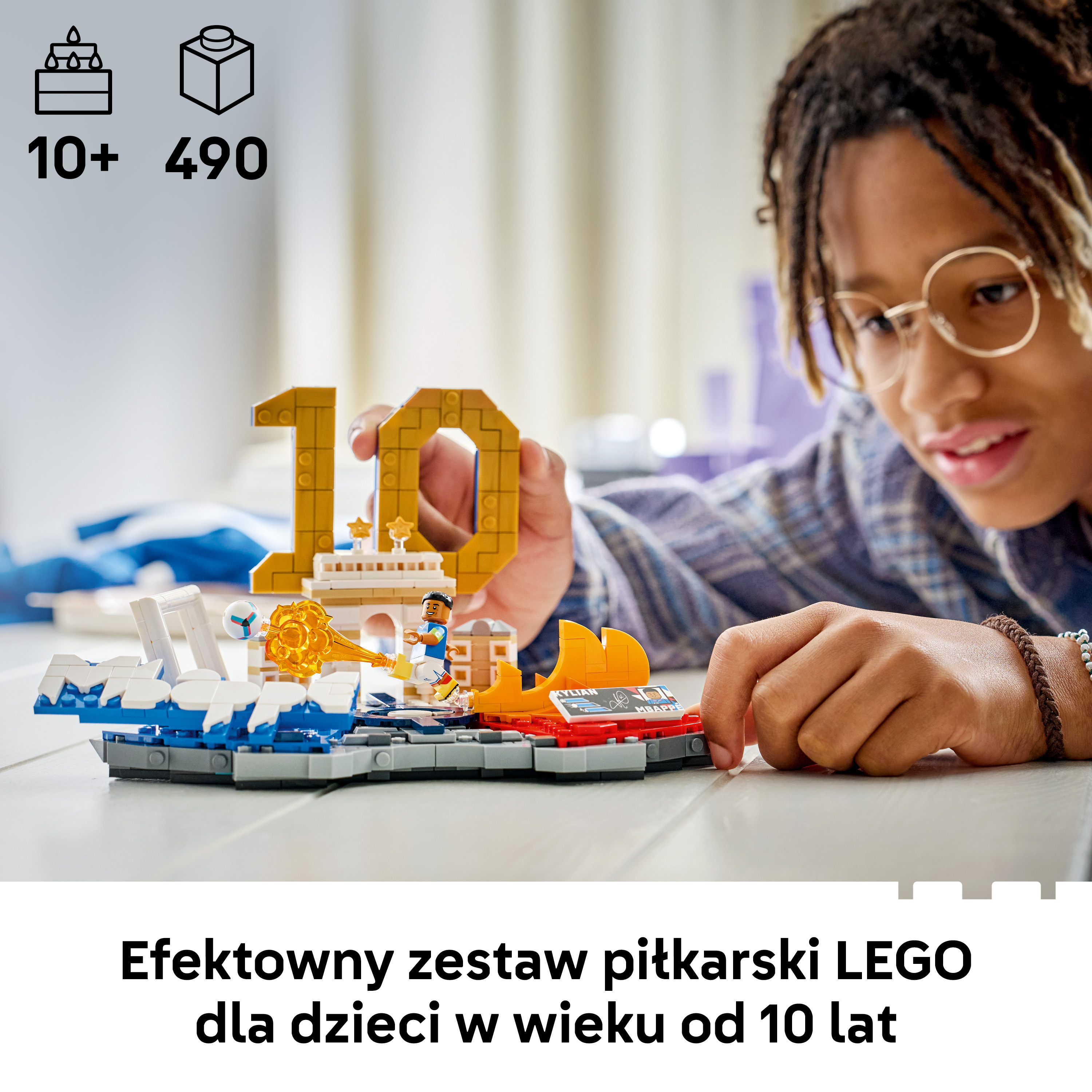 Chłopiec w okularach buduje zestaw piłkarski LEGO z Kylianem Mbappé.