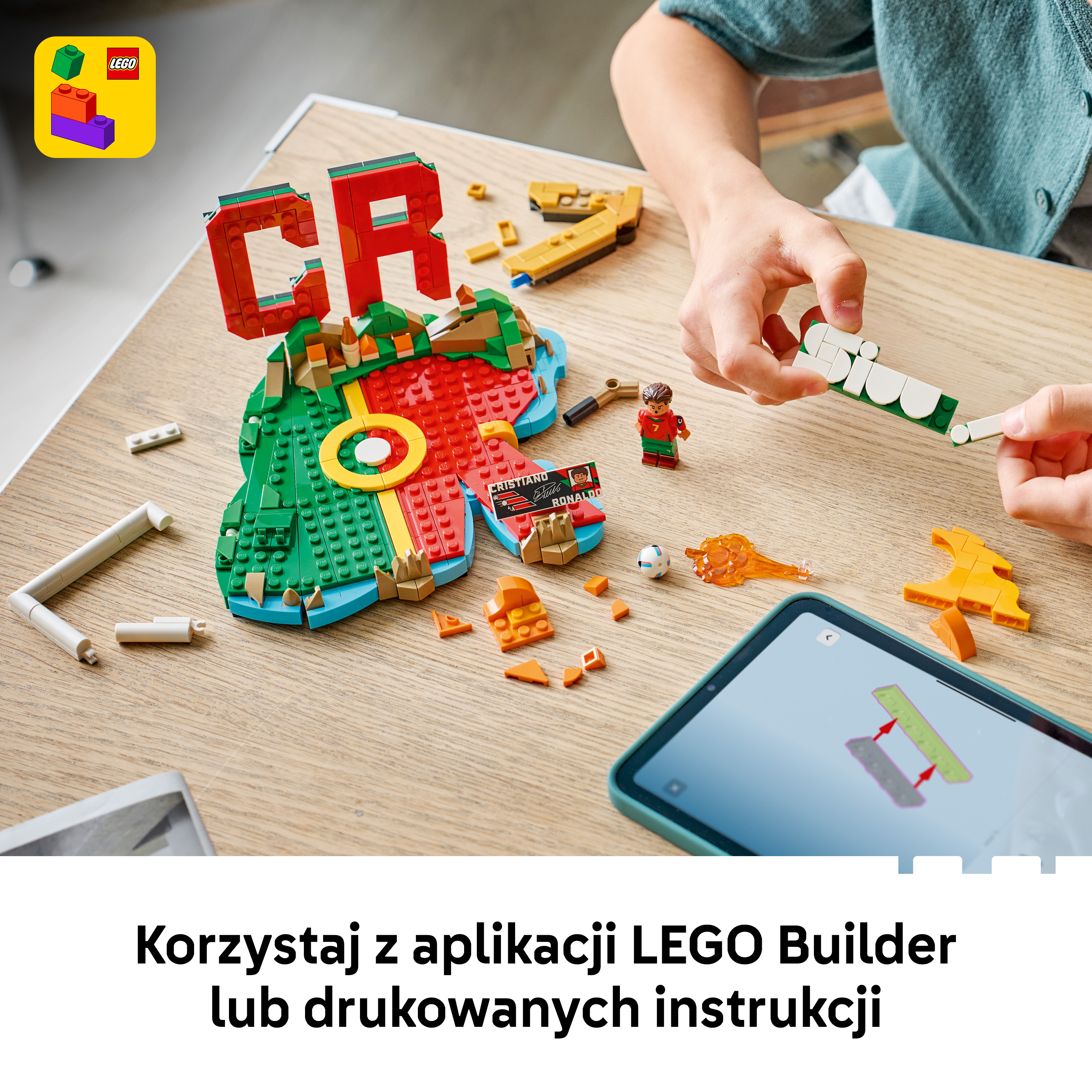 Osoba buduje z klocków LEGO; instrukcje widoczne na tablecie.