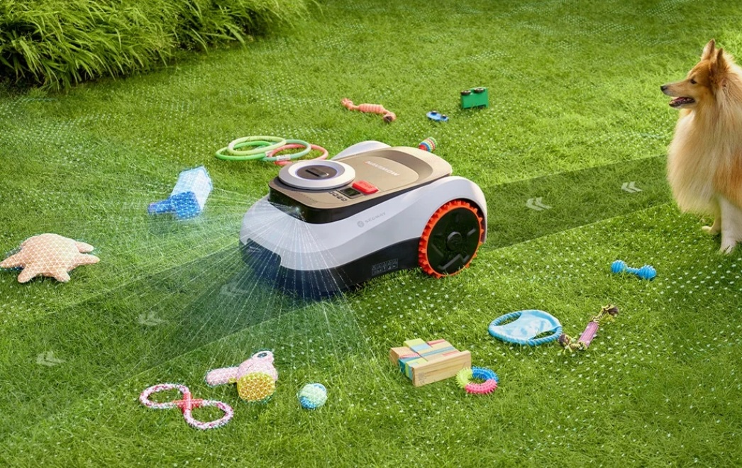 Robot koszący na trawniku z psem i zabawkami. Pryska woda.