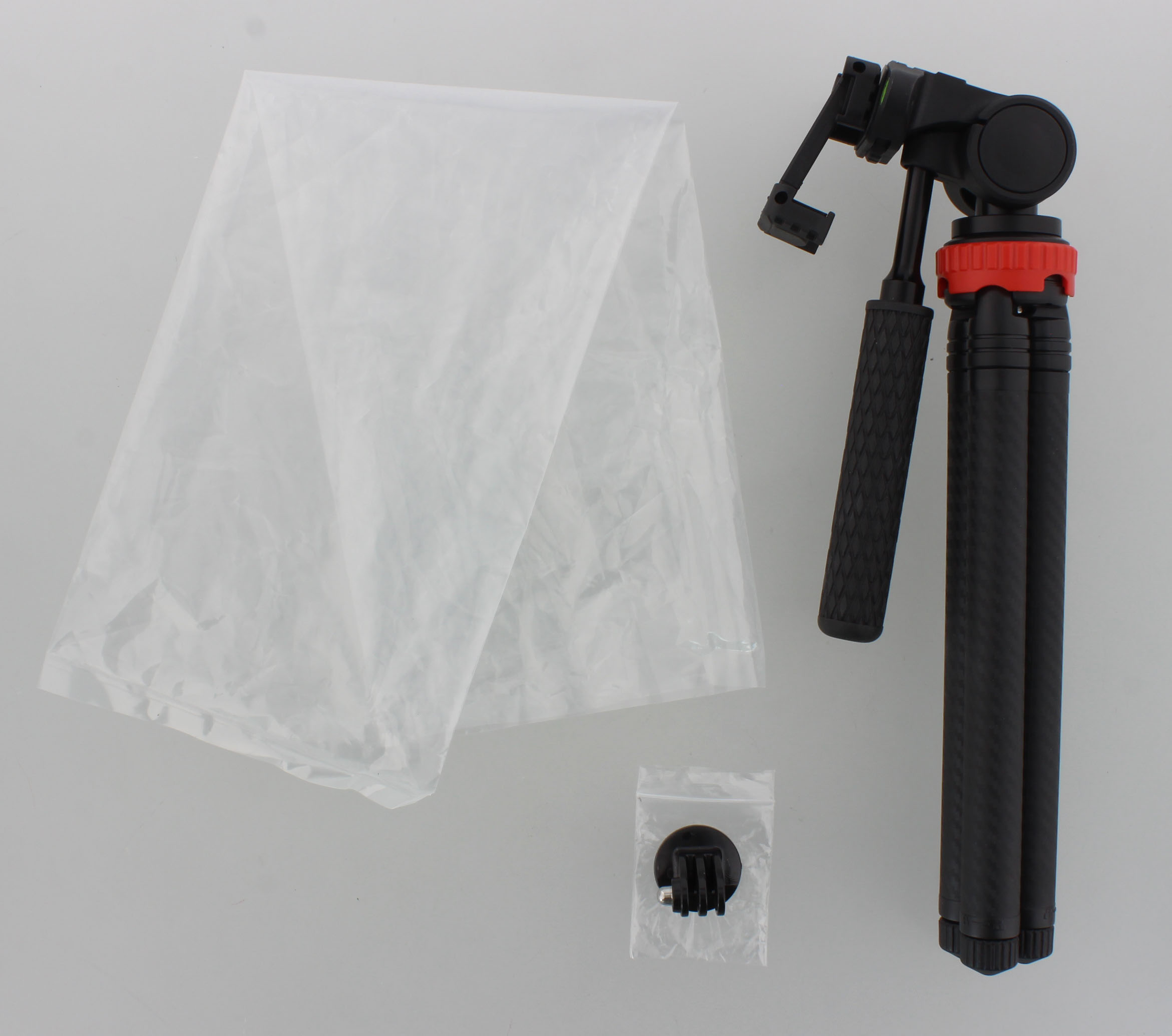 Kırmızı halkalı siyah bir tripod, beyaz bir bez ve poşet içinde küçük bir montaj parçası.