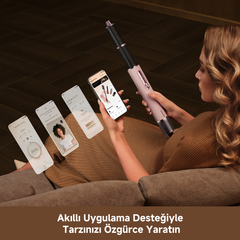Kadın pembe saç şekillendirici ve uygulama yüklü telefon tutuyor. Uygulama stil seçenekleri.