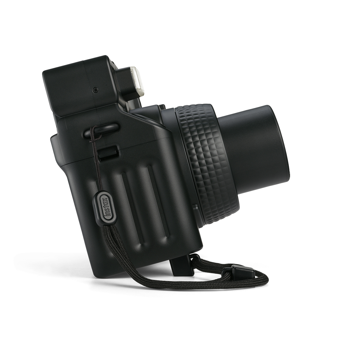 Lens halkası ve flaşı olan siyah anında fotoğraf makinesi, Instax logosu taşıyor.