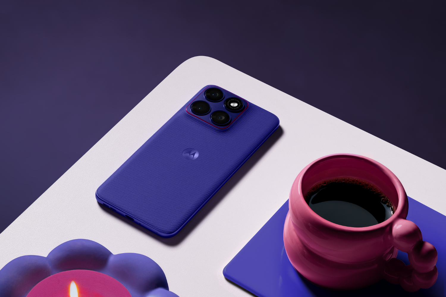 Fioletowy smartfon leży obok różowego kubka kawy na białej powierzchni.