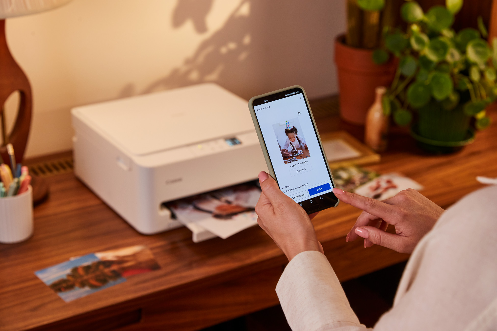 Telefon wyświetla zdjęcie tortu urodzinowego; drukarka drukuje zdjęcia.