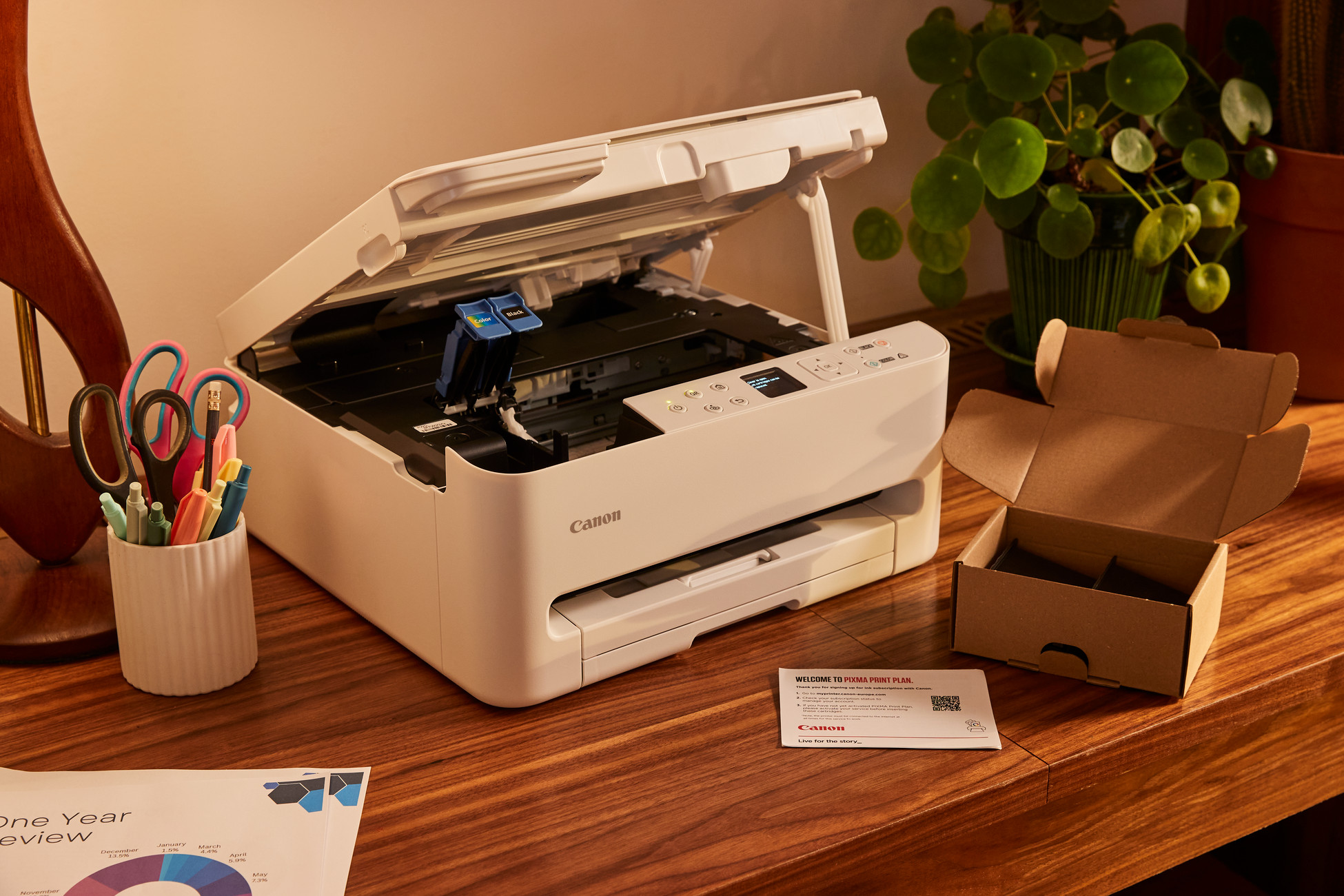 Biała drukarka Canon z otwartą pokrywą, widoczne wkłady z tuszem.