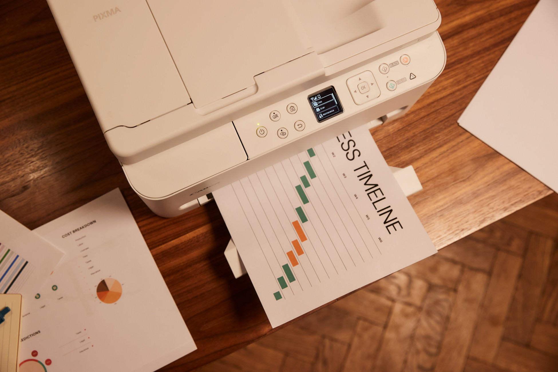 Biała drukarka drukuje wykres osi czasu firmy na drewnianym biurku.