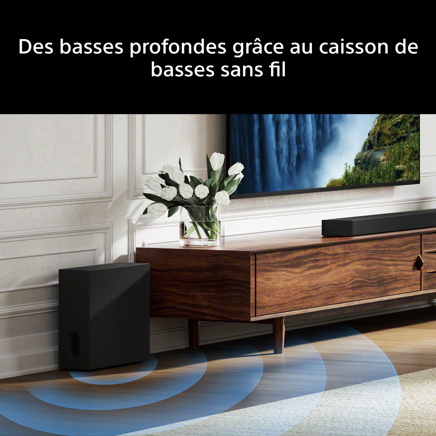 Caisson de basses noir à côté d'un meuble en bois avec TV et fleurs. Ondes bleues indiquent le son.