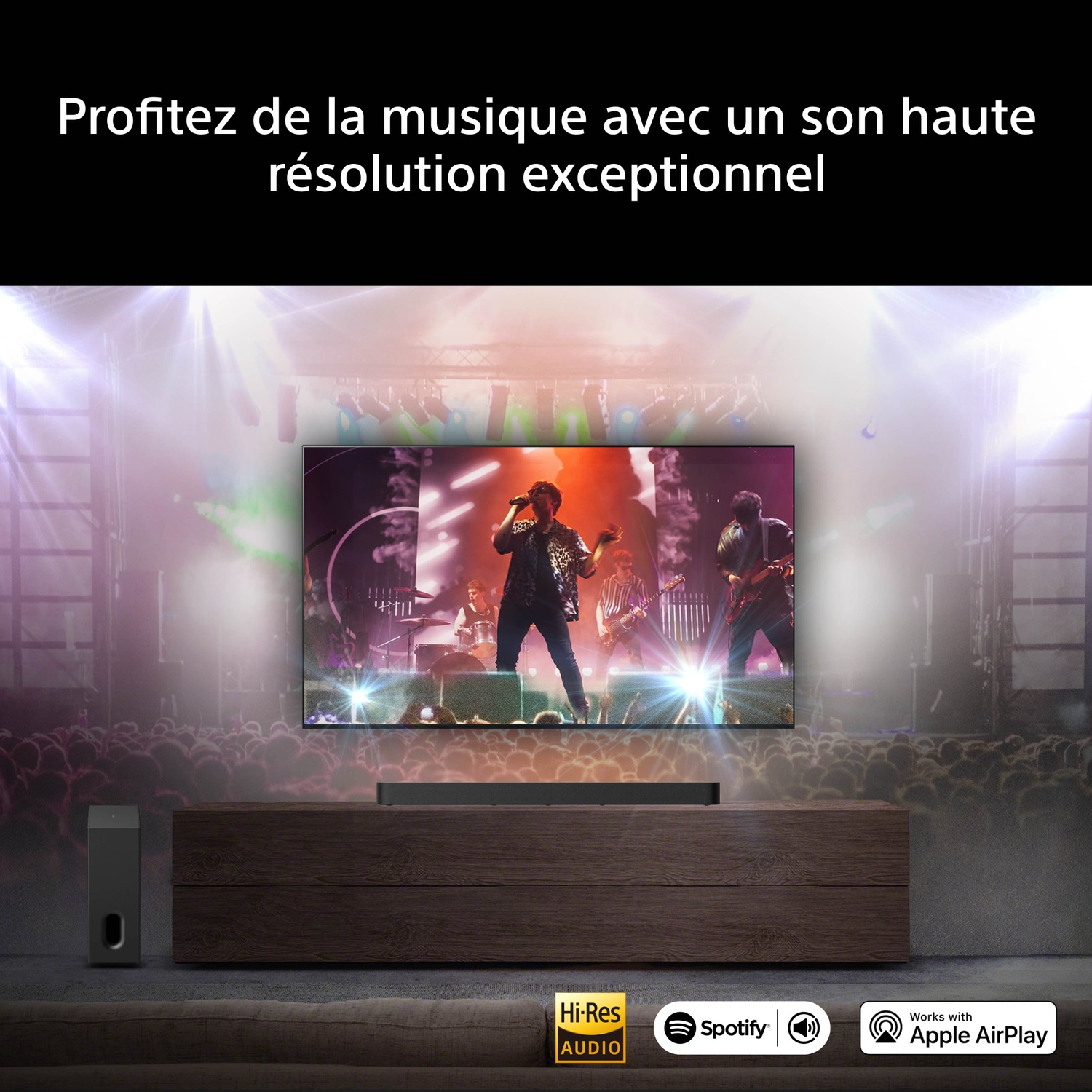 Un écran de télévision montre un groupe en concert, avec une barre de son à côté.