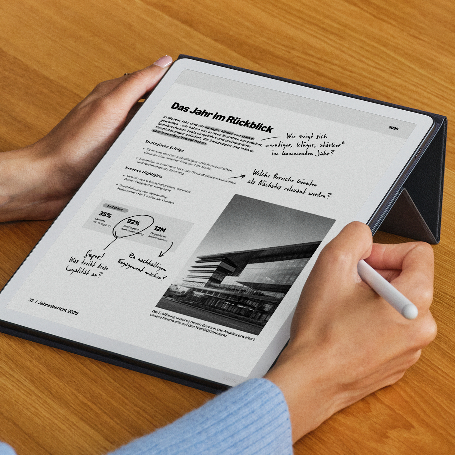 Eine Person hält ein Tablet mit einem Jahresbericht. Darauf sind Diagramme, Text und ein Gebäude zu sehen.