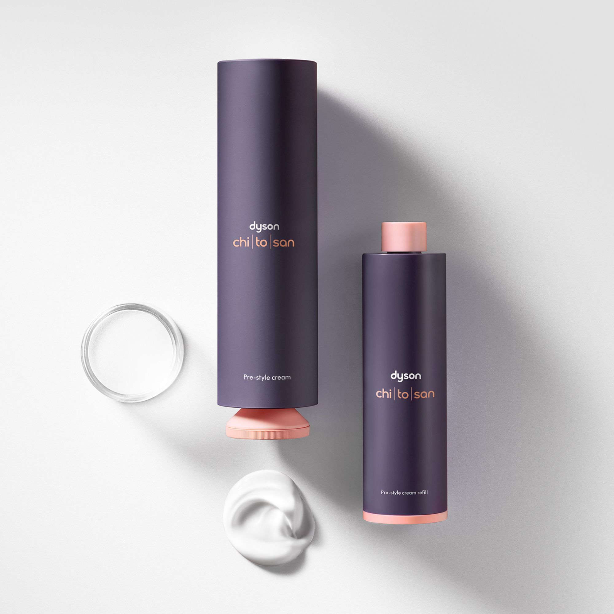 Zwei Dyson Pre-Style Cream Flaschen, eine mit Creme-Klecks und Deckel.