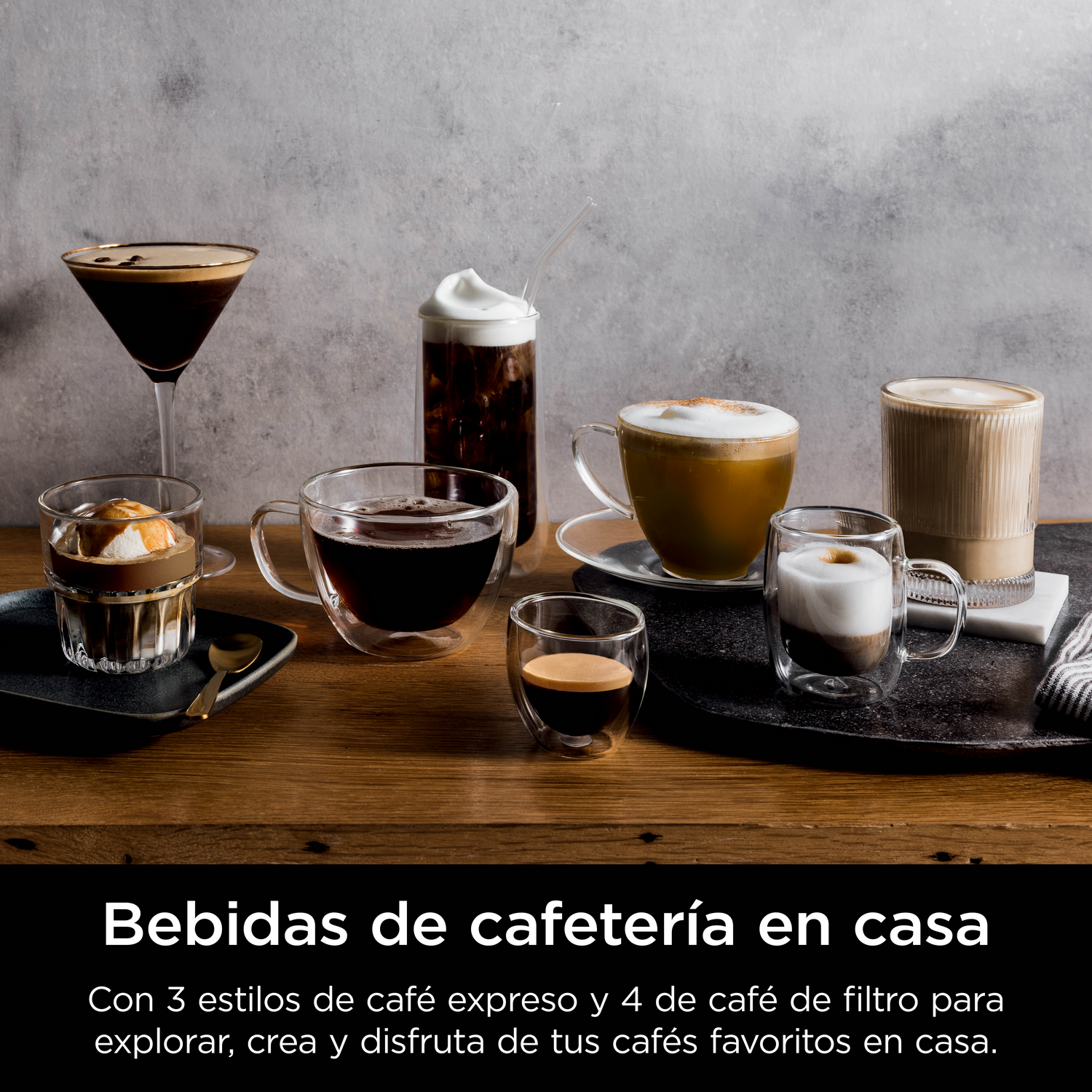 Varias bebidas de café sobre una mesa de madera contra pared de hormigón.