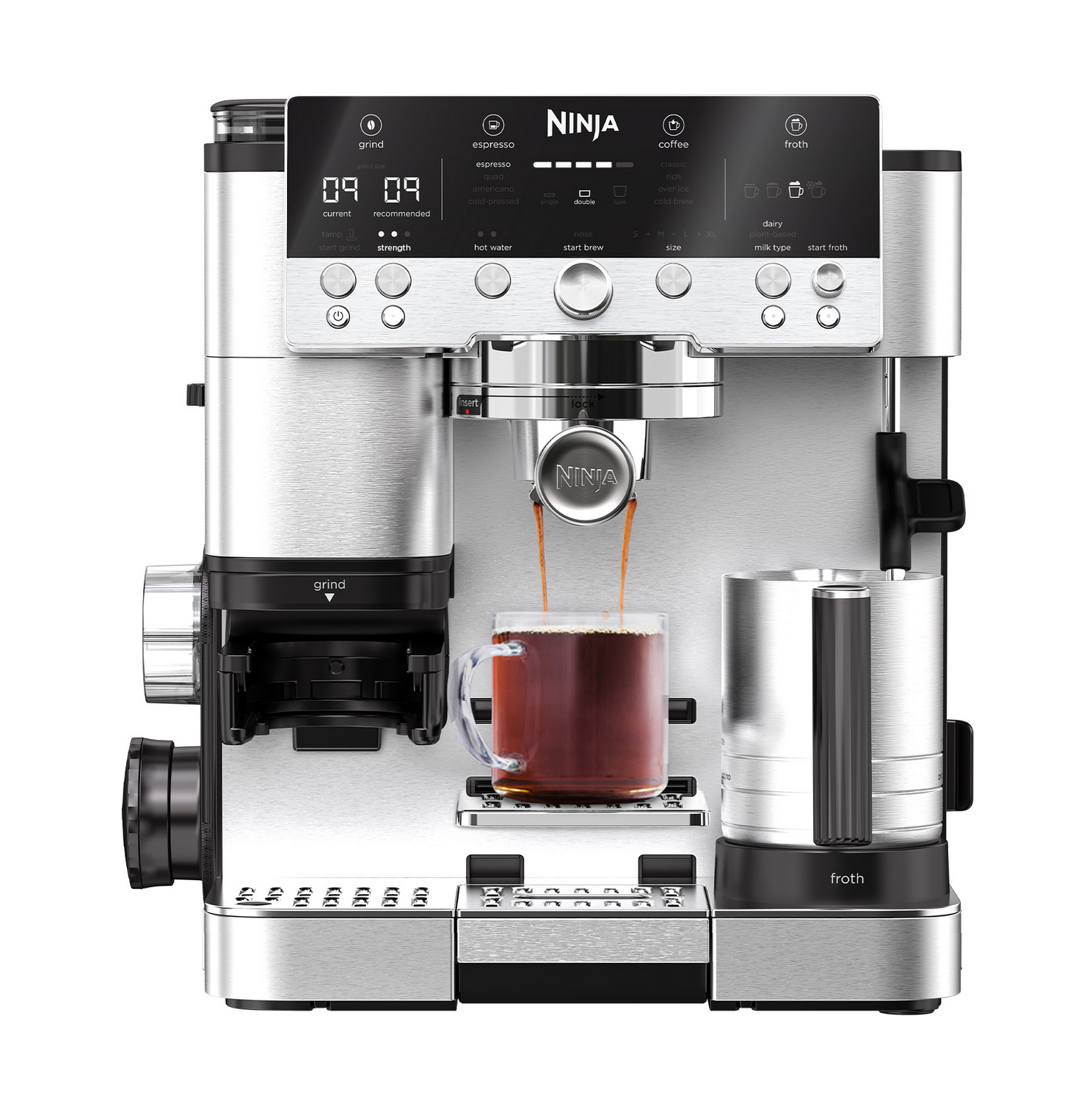 Una cafetera Ninja plateada prepara café en una taza transparente con una jarra de leche al lado.