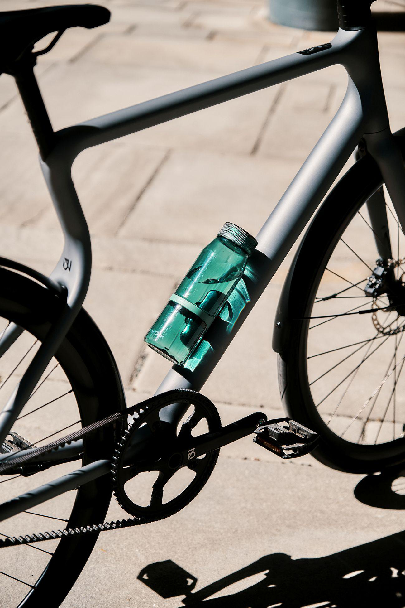 Graues Fahrrad mit grüner Wasserflasche am Rahmen. Nahaufnahme des Antriebsstrangs.