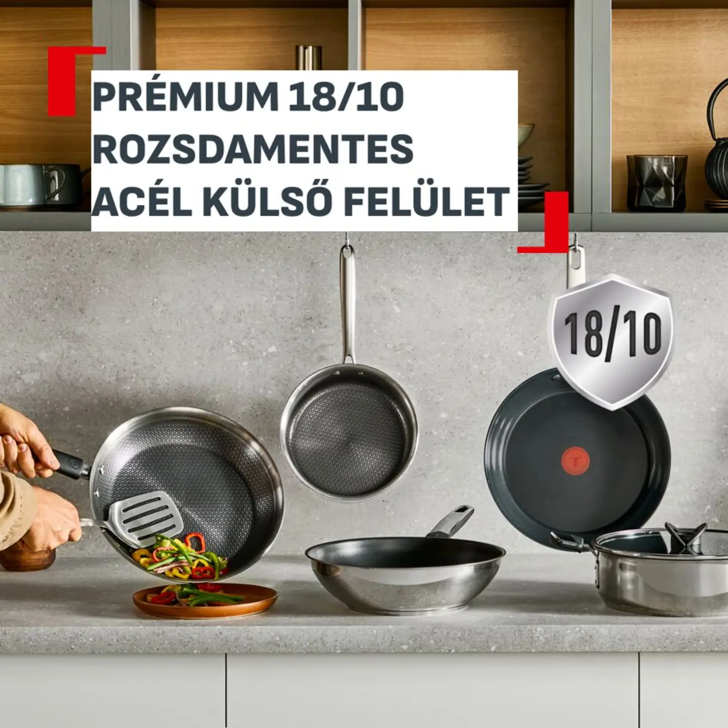 Különböző rozsdamentes acél serpenyők és egy lábas látható a pulton. Egy serpenyő döntve, étel tálalva.