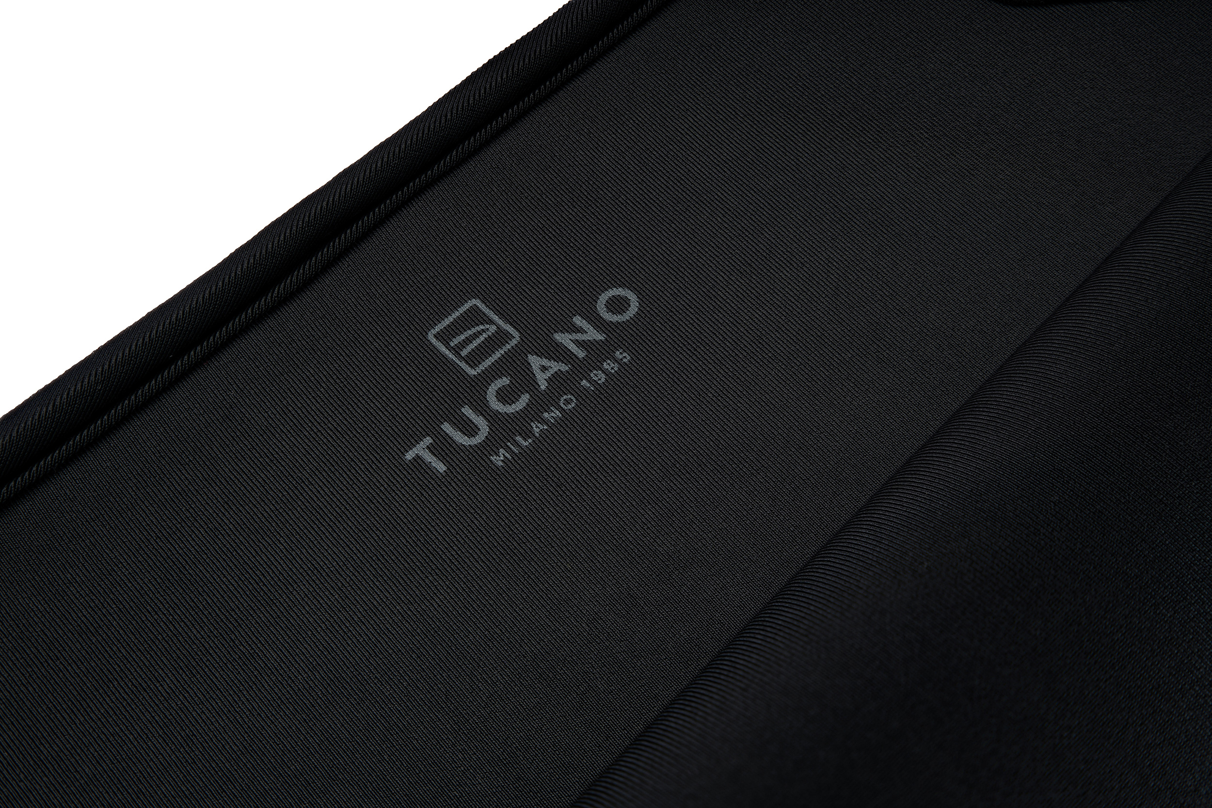 Tessuto nero con logo Tucano in rilievo e "Milano 1995".