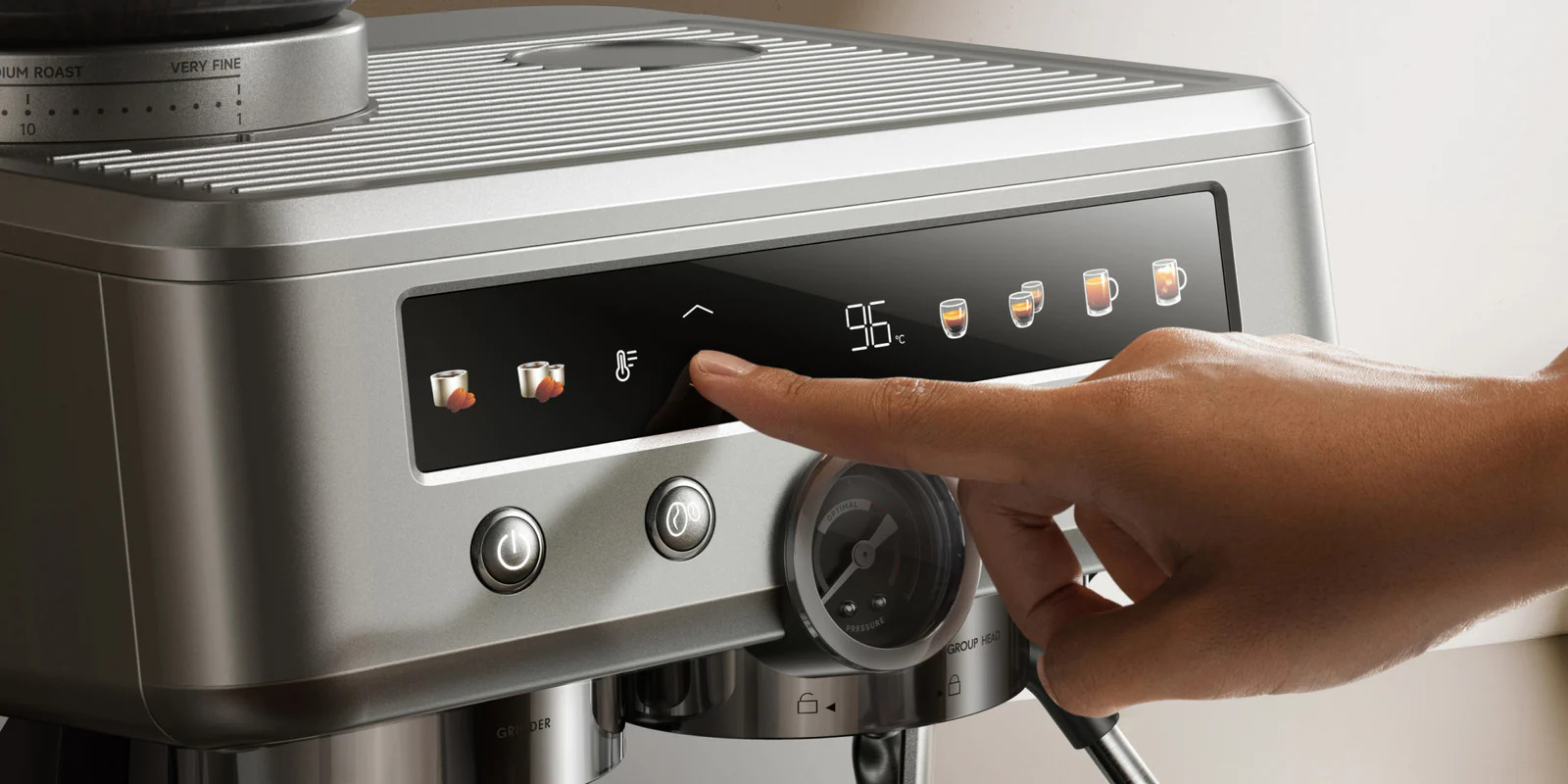 Dłoń obsługuje srebrny ekspres do kawy z cyfrowym wyświetlaczem.