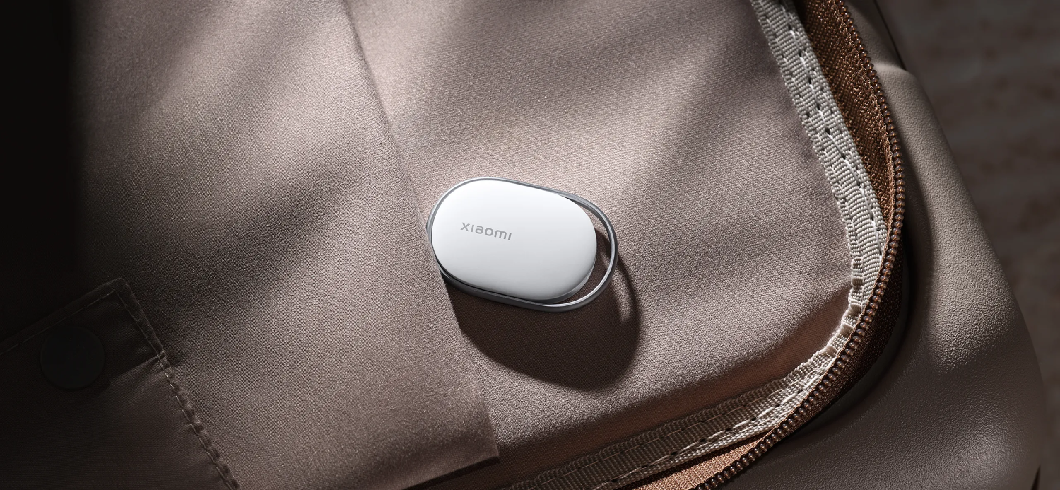 Un dispositivo Xiaomi blanco descansa sobre tela beige junto a una cremallera.