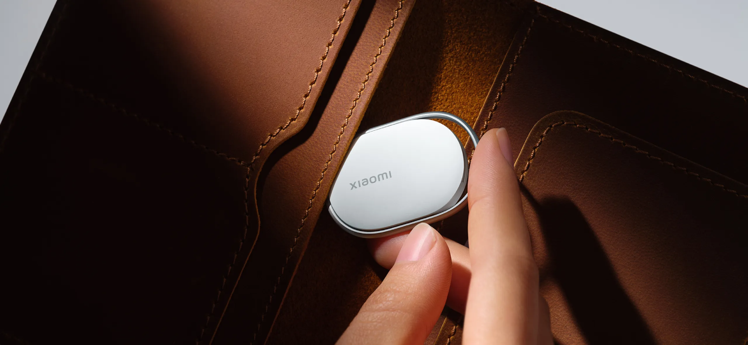 Una mano sostiene una etiqueta plateada de Xiaomi en una cartera de cuero marrón.