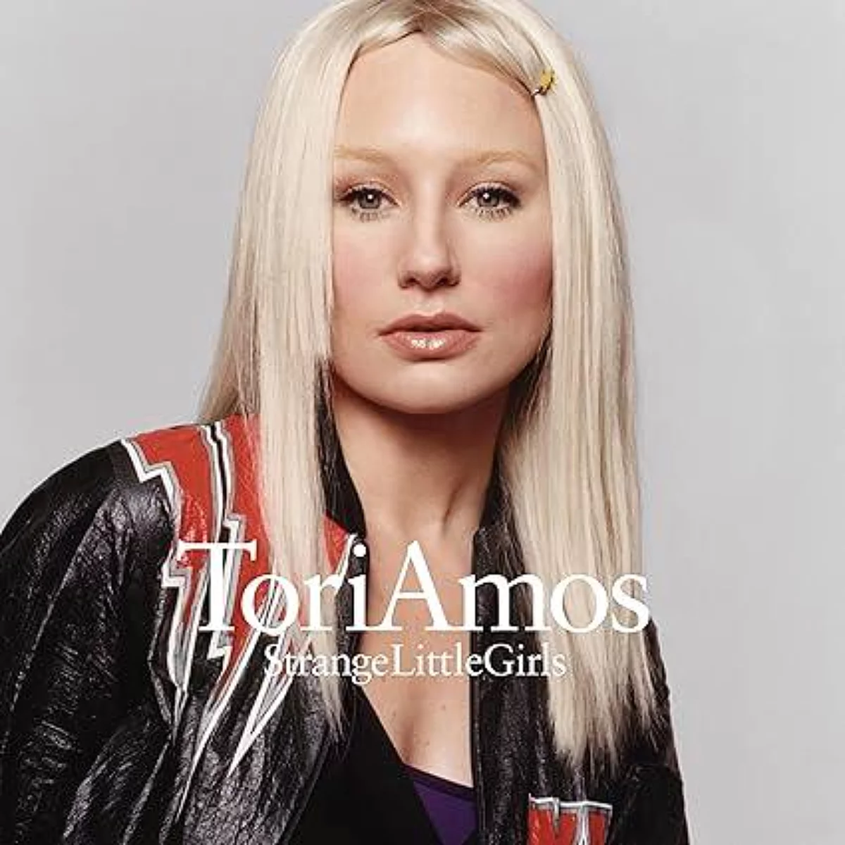 Tori Amos met blond haar draagt een leren jas met rode strepen. Tekst: Tori Amos Strange Little Girls.