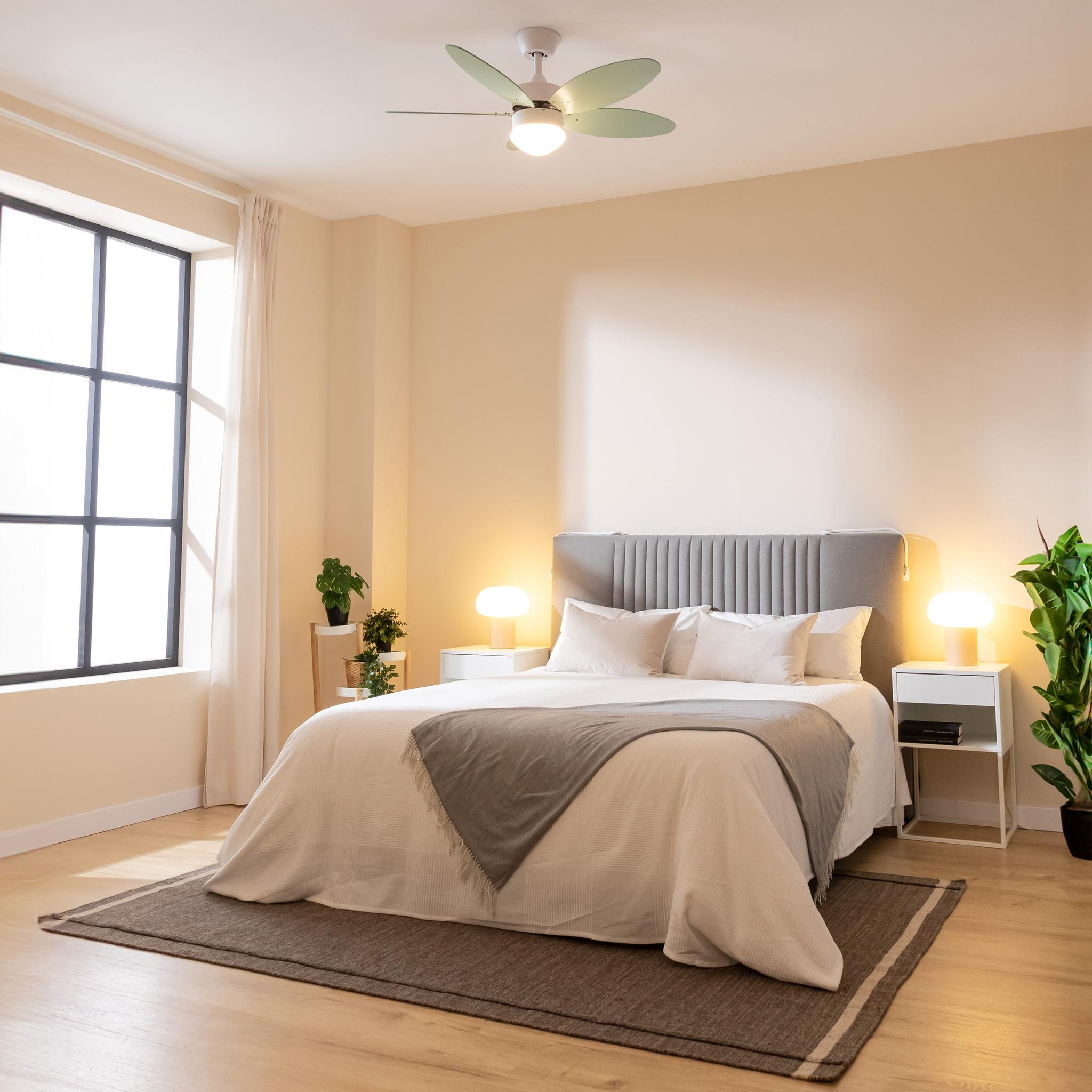 Un dormitorio con cama, mesitas de noche, lámpara, alfombra y ventana.