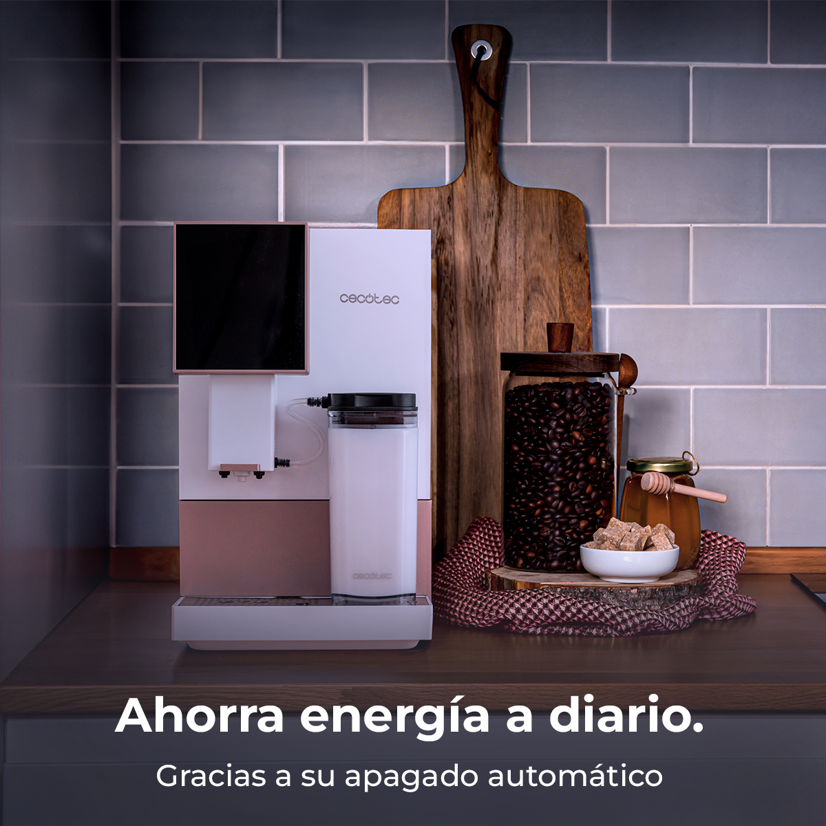 Una cafetera blanca con detalles oro rosa junto a granos de café y miel.