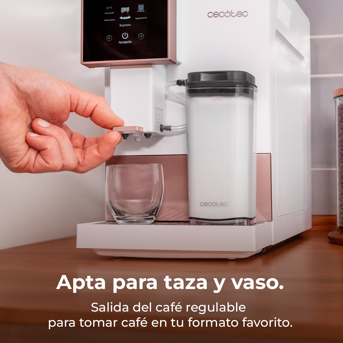 Una mano opera una cafetera con depósito de leche y vaso. La pantalla muestra opciones.