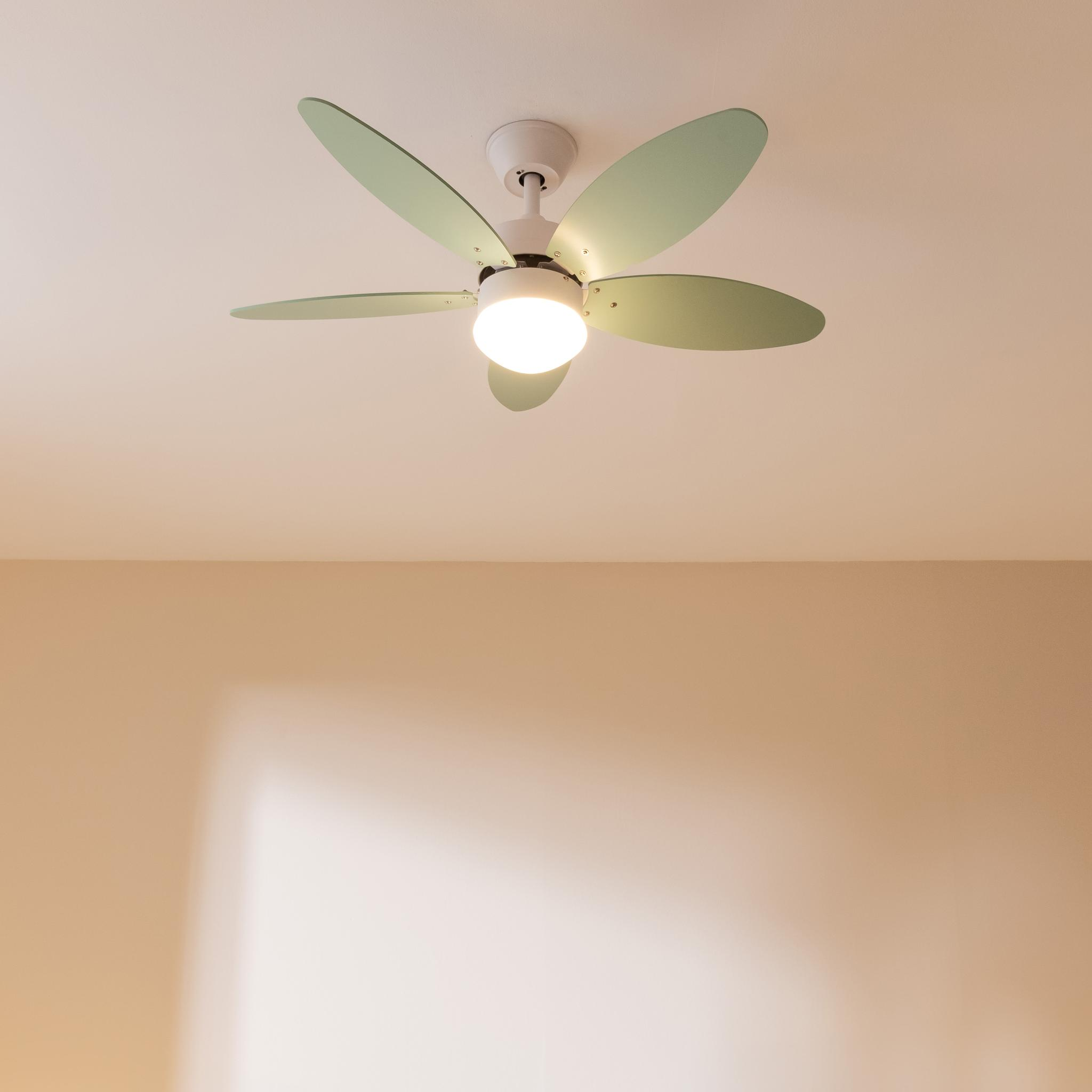 Un ventilador de techo blanco con cinco aspas verde claro y luz central está montado en un techo blanco.