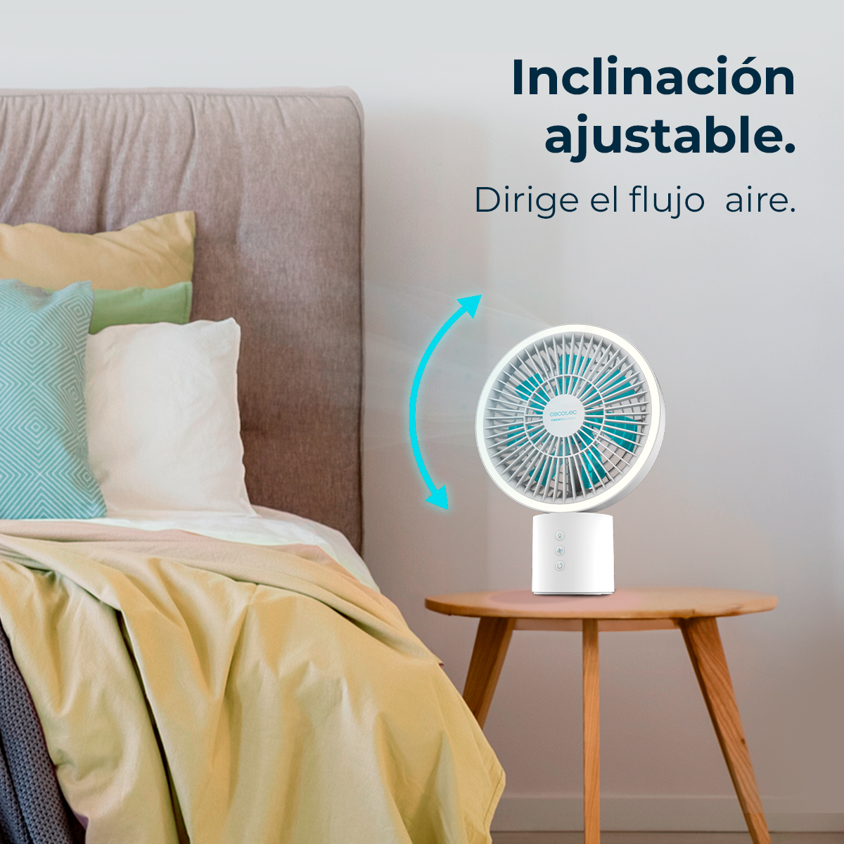 Un ventilador blanco con aspas azules sobre mesa de madera junto a una cama.