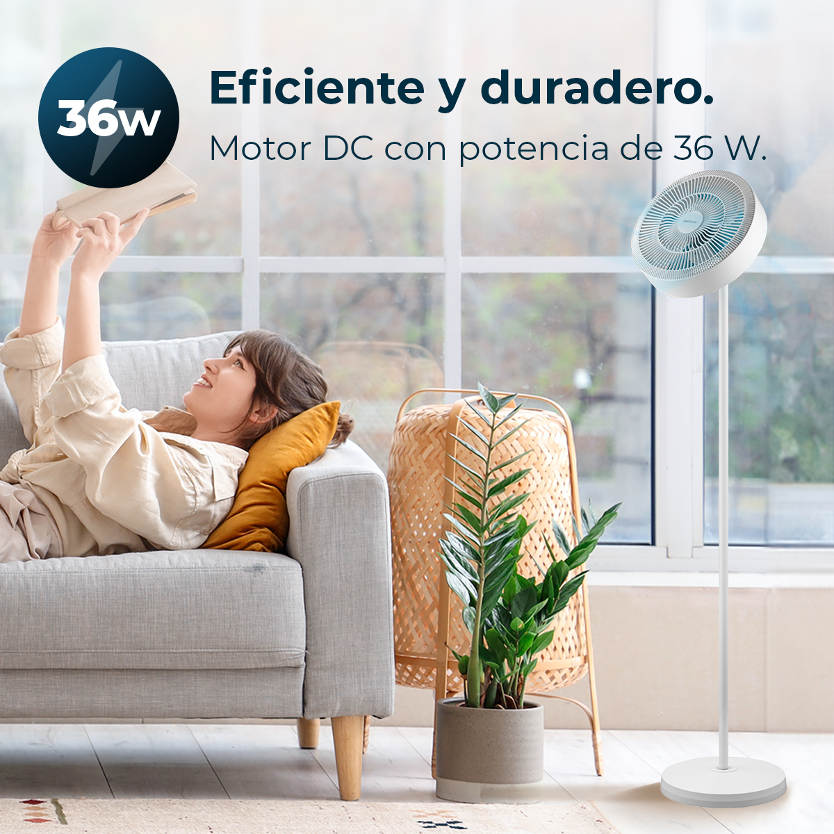 Una mujer se reclina en un sofá leyendo. Un ventilador está cerca.