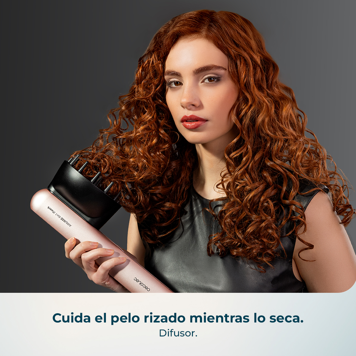 Mujer con pelo rojo rizado sostiene un difusor rosa.