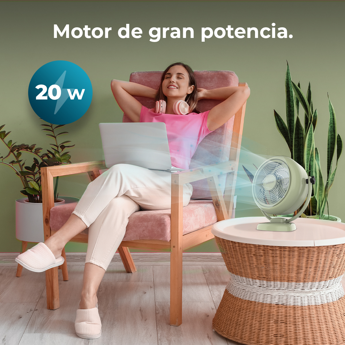 Mujer relajándose con portátil y auriculares, un ventilador sopla aire fresco.