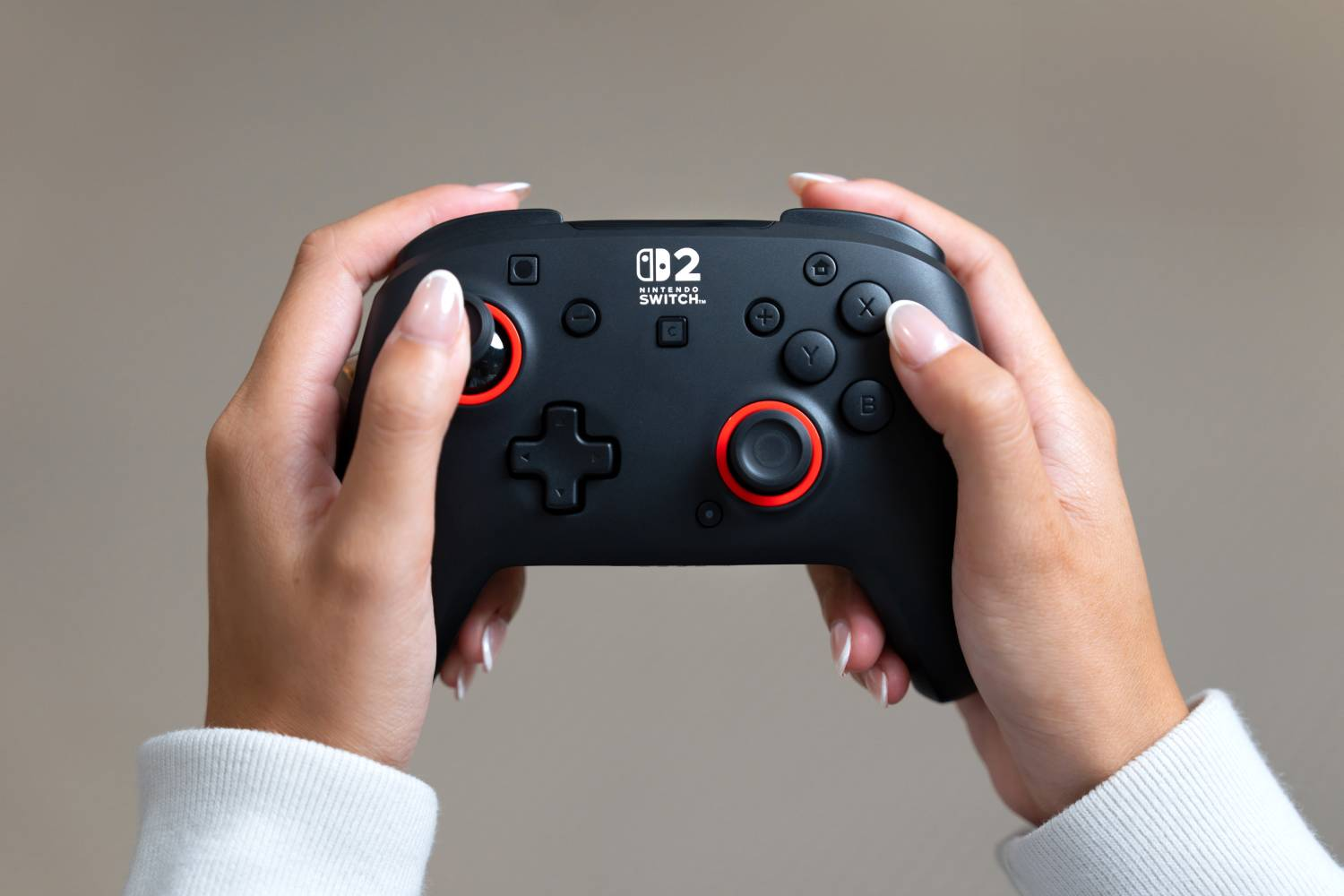 Persona sujetando un mando negro de Nintendo Switch con detalles rojos.