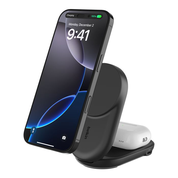 Un soporte de carga negro con iPhone y AirPods, sobre una superficie blanca.
