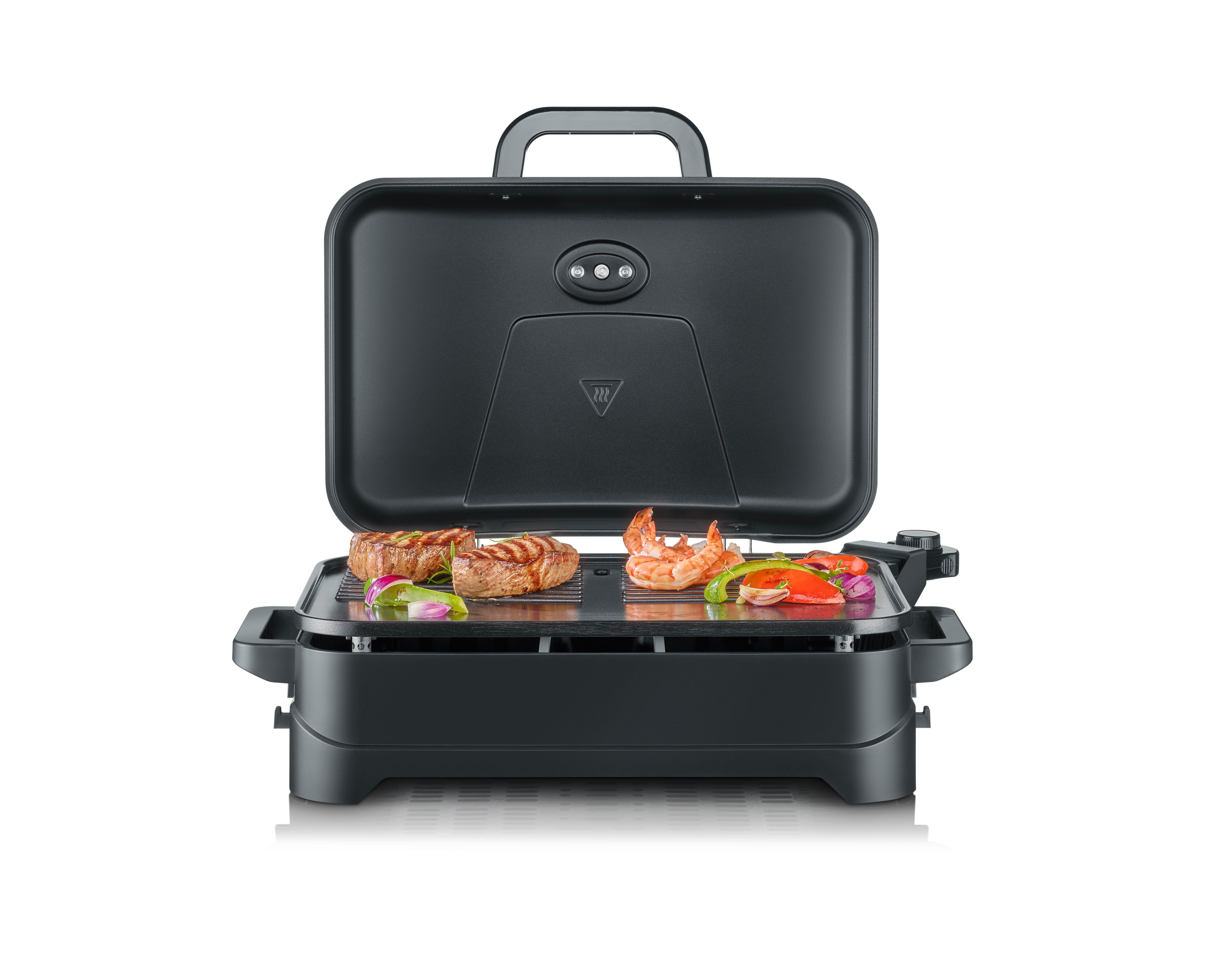 Ein schwarzer Tischgrill mit offenem Deckel, auf dem Steaks, Garnelen und Gemüse gegrillt werden.