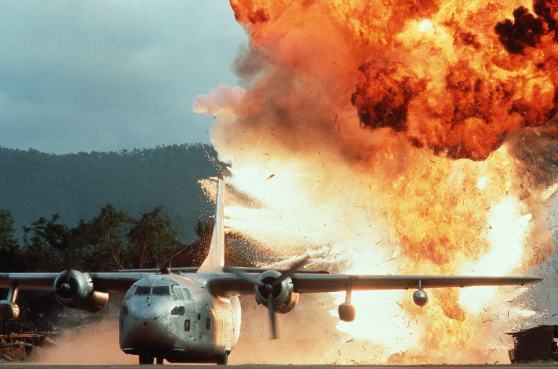 Ein Flugzeug auf einer Landebahn explodiert im Hintergrund.