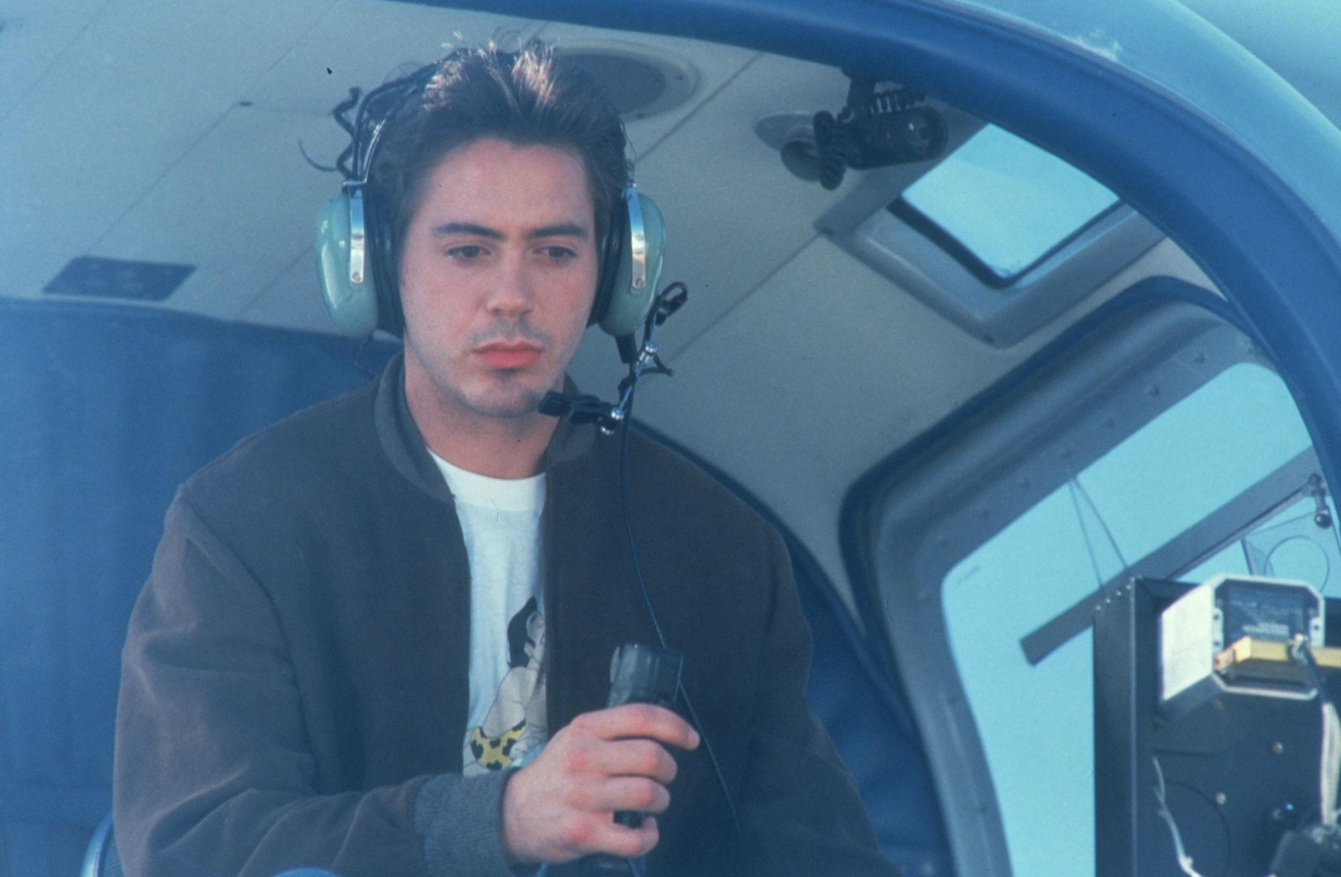 Mann mit Kopfhörern im Helikopter hält ein Mikrofon.