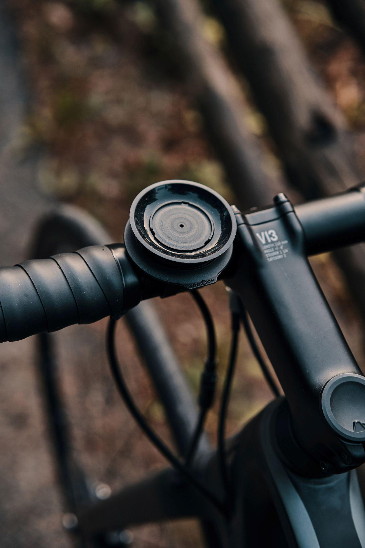 Nahaufnahme eines schwarzen Fahrradlenkers mit einer runden Halterung und Kabeln.