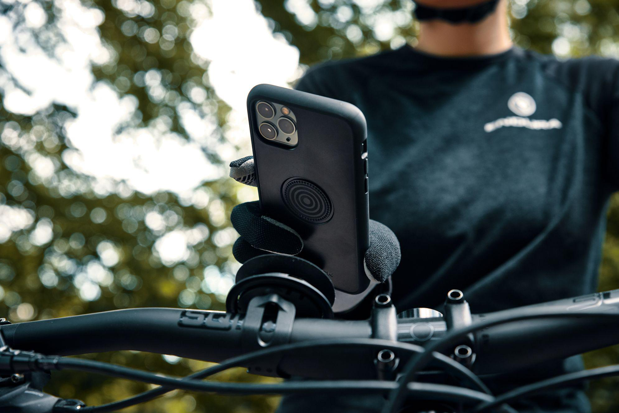 Ein Handyhalter an einem Fahrradlenker mit einem Mann im Hintergrund.