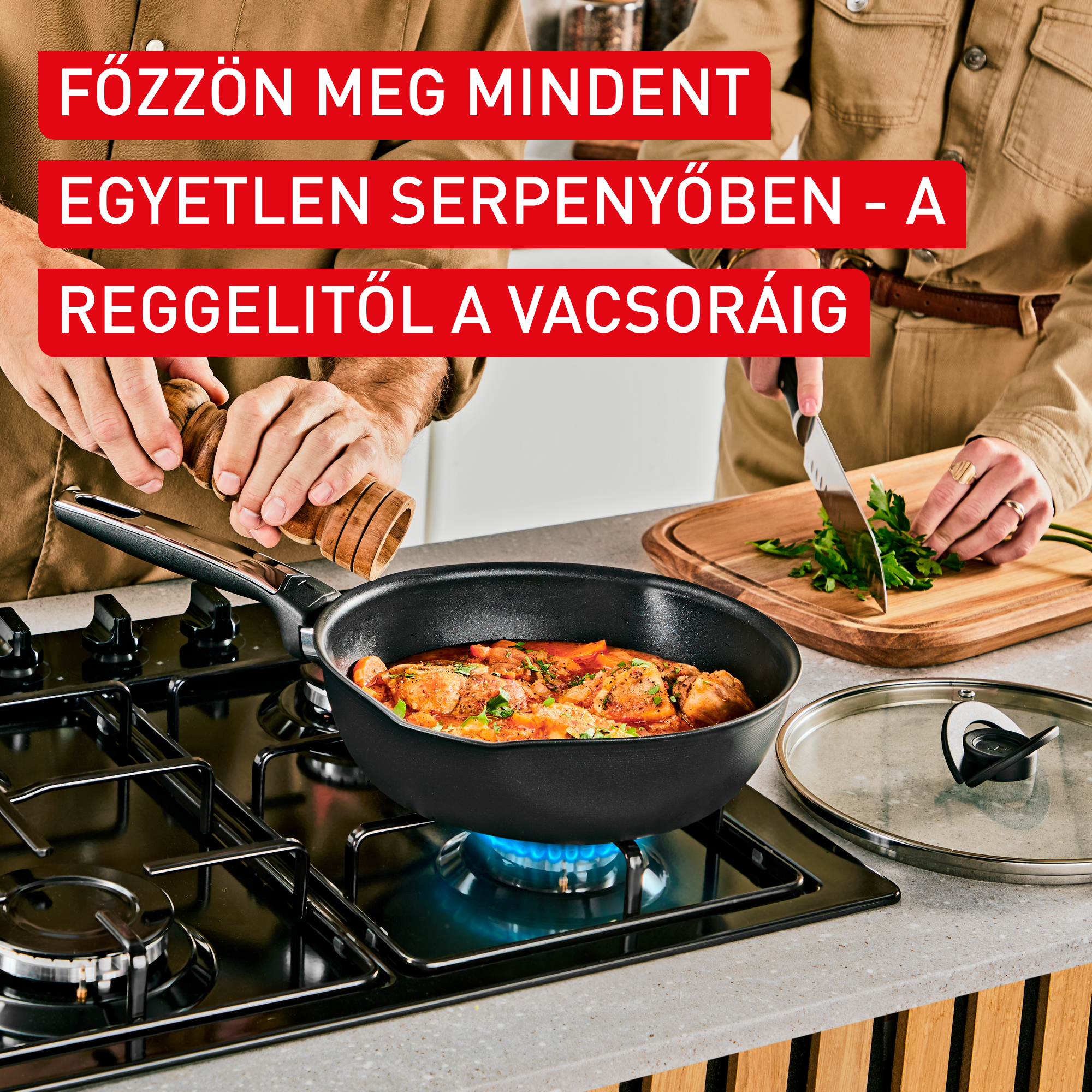 Két személy főz egy serpenyőben gáztűzhelyen. Az egyik fűszerez, a másik fűszernövényt vág.
