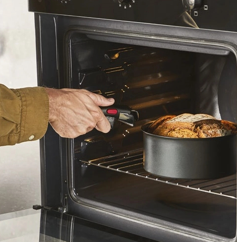 Mężczyzna używa chwytaka do wyjmowania chleba z piekarnika.