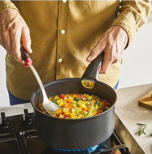 Osoba gotująca gulasz warzywny w garnku na kuchence gazowej.