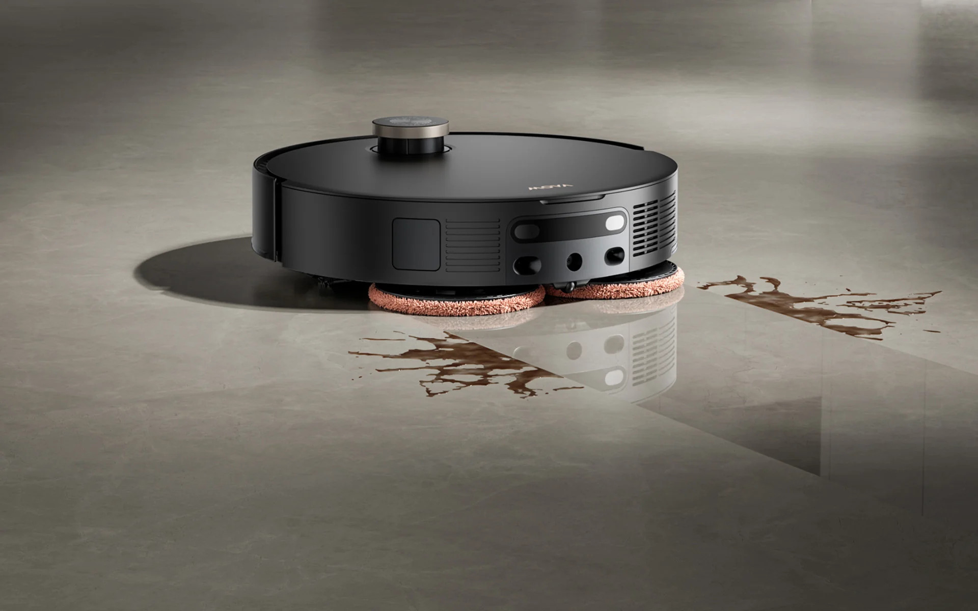 Czarny robot sprzątający z obrotowymi padami mopującymi czyści brudną podłogę.