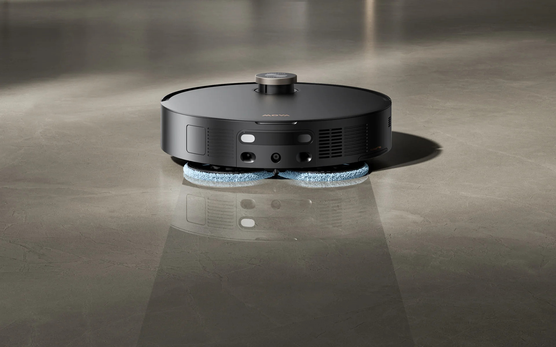 Czarny robot sprzątający z niebieskimi szczotkami czyści błyszczącą kamienną podłogę.