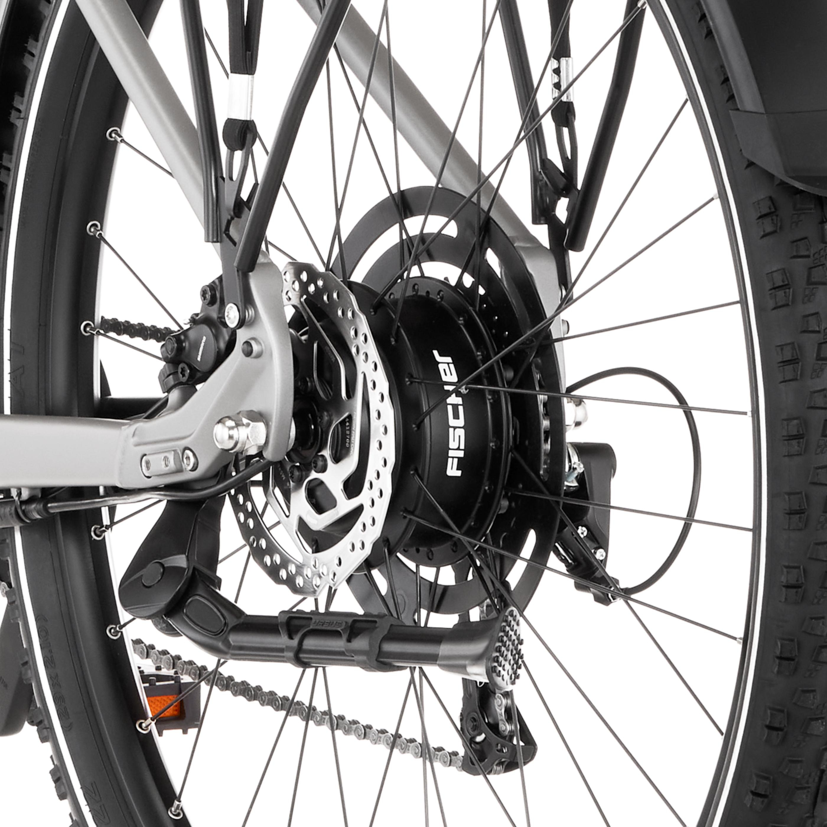 Nahaufnahme des Hinterrads eines silbernen E-Bikes mit Kette, Bremsscheibe und Motor.