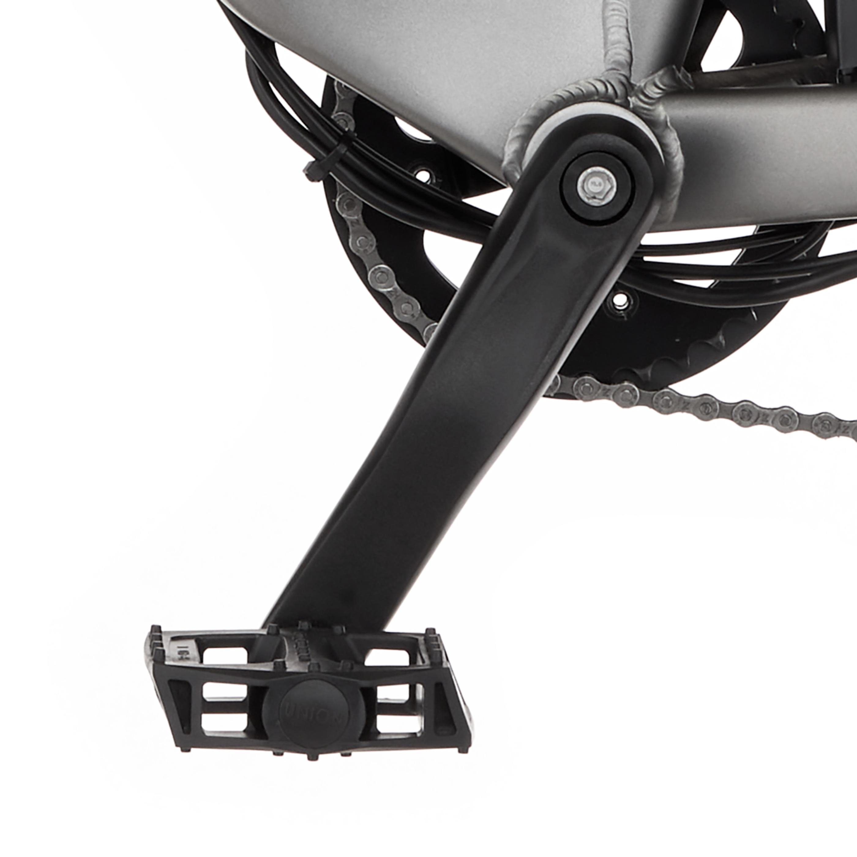 Nahaufnahme eines Fahrradpedals mit Kurbel und Kette an einem silbernen Rahmen.