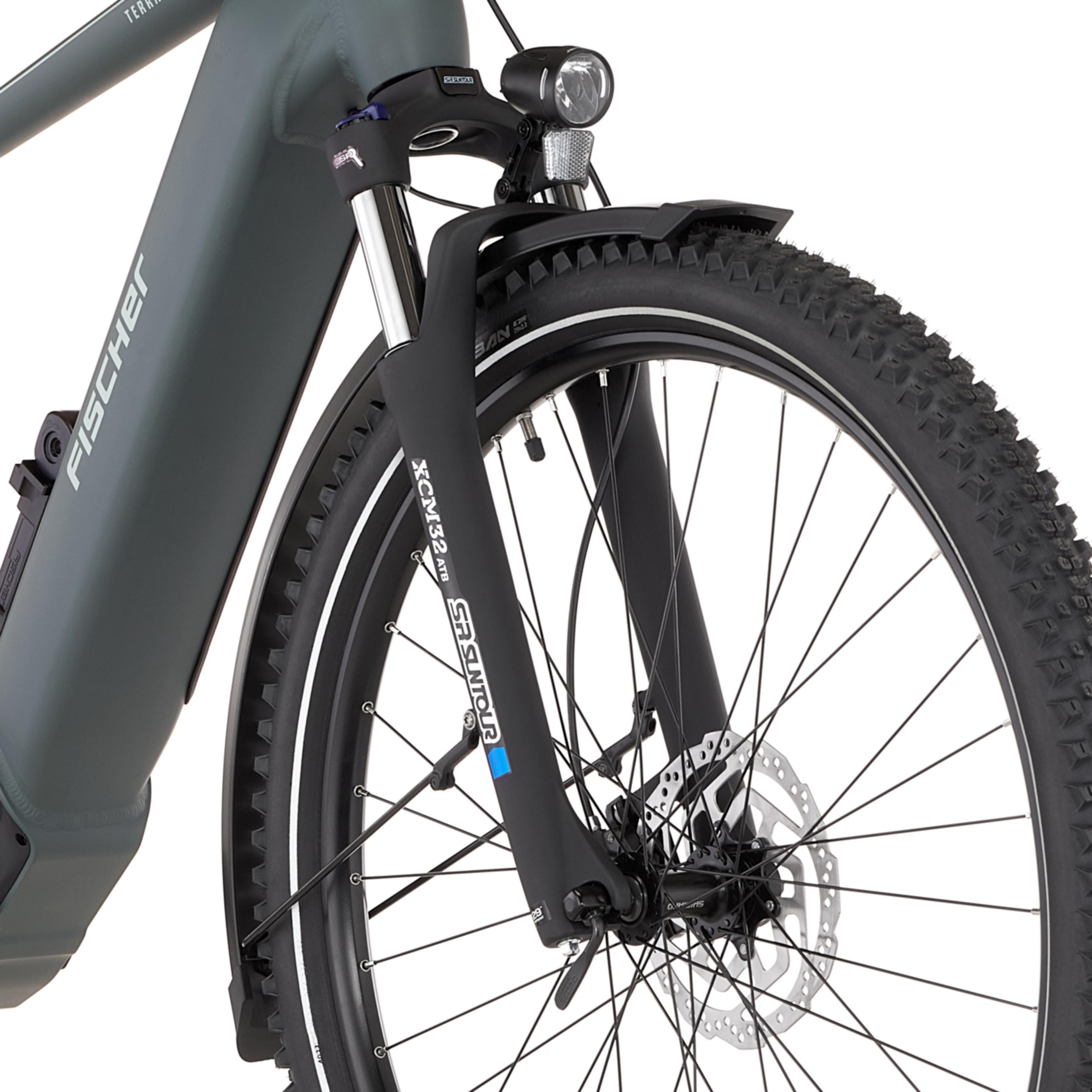Graues Fahrrad mit Federgabel, Scheinwerfer und grobstolligem Reifen.